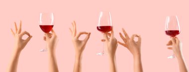 Kırmızı şarap kadehlerini tutan kadın elleri pembe arka planda iyi görünüyor. 