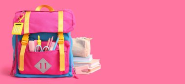 Okul çantası ve pembe zemin üzerinde kırtasiye malzemesi ve metin için boşluk