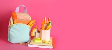 Okul çantası ve pembe zemin üzerinde kırtasiye malzemesi ve metin için boşluk