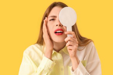 Sarı arka planda gözlerini kontrol eden genç bir kadın, yakın plan.