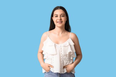 Mavi arka planda beyaz bluzlu güzel bir kadın.