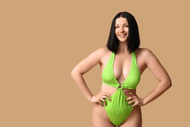 Kahverengi arka planda zarif yeşil mayo giyen güzel bir kadın.