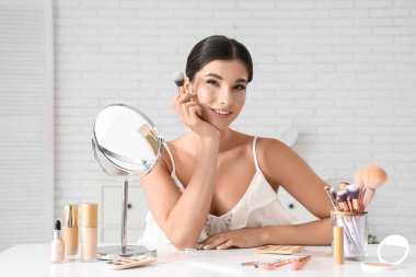 Makyaj fırçaları ve kuafördeki farklı kozmetik ürünleri olan güzel bir kadın.