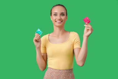 Yeşil arka planda prezervatifli genç bir kadın.