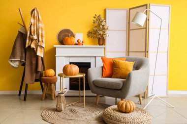 Oturma odasının içinde koltuk, şömine ve sonbahar dekoru var.