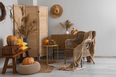 Sonbahar için tasarlanmış modern oturma odasının içi rahat hasır koltuklar ve balkabaklarıyla süslenmiş.