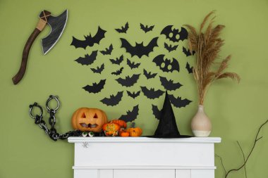 Cadılar Bayramı için dekore edilmiş şömine, oturma odasındaki yeşil duvarın yanında.