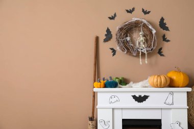 Oturma odasındaki bej duvarın yanında Cadılar Bayramı dekorlu şık şömine rafı.