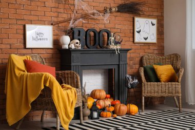 Cadılar Bayramı dekorasyonlu şömine, koltuklar ve tuğla duvarın yanında balkabakları