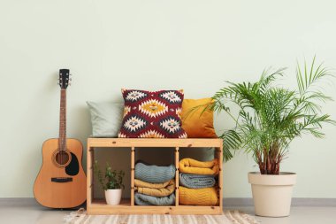 Katlanmış battaniyeleri, gitarı ve palmiyesi olan bir oda.