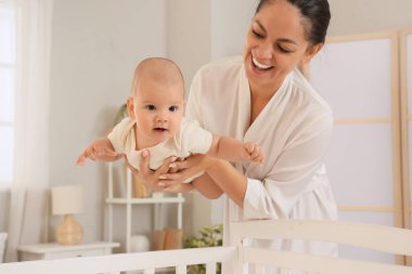 Anne küçük bebeğini yatak odasında tutuyor.