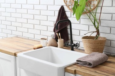 Banyodaki beyaz tuğla duvarın yanında banyo aksesuarlarıyla lavabo.