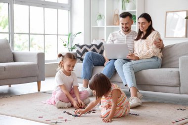 Aileleri evdeki kanepede otururken mutlu kız kardeşler oynuyorlar.