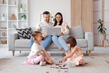 Aileleri evdeki kanepede otururken mutlu kız kardeşler oynuyorlar.