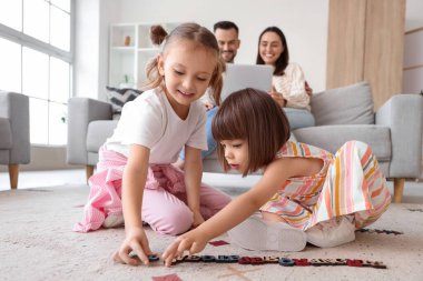 Aileleri evdeki kanepede otururken mutlu kız kardeşler oynuyorlar.