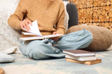 Evinde yerde kitap okuyan güzel genç bir kadın, yakın çekim.