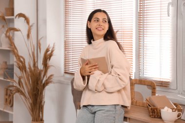 Evinde kitabı olan güzel, mutlu bir kadın.