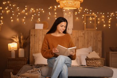 Güzel, genç, mutlu bir kadın akşamları bankta kitap okuyor.