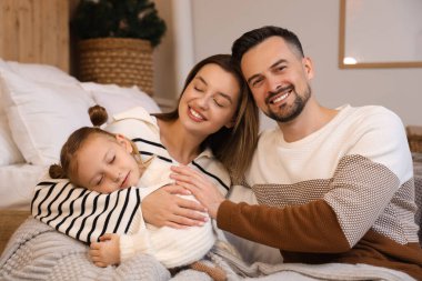 Mutlu ebeveynler ve küçük kızları kış akşamı evde uyuyorlar.