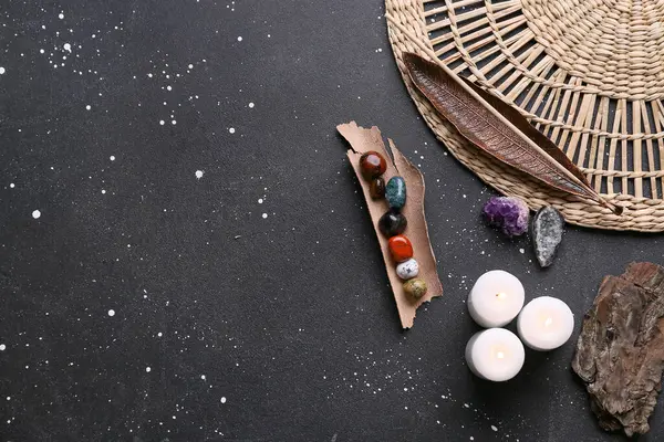 Koyu arkaplanda çakra taşları, tütsü ve mumlar.