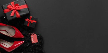 Kadın ayakkabıları, giysileri ve karanlık arka planda hediye kutuları. Mesaj için yer var. Kara Cuma indirimi