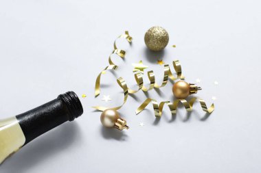 Gri arka planda yeni yıl partisi için bir şişe şampanya ve dekorasyonla harika bir kompozisyon.