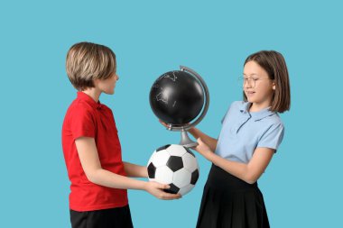 Mavi arka planda futbol topu ve küresi olan okul üniformalı sevimli çocuklar.