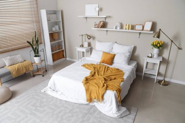 Yatak odasının içinde sarı ekose ve yastıklı beyaz rahat bir yatak.