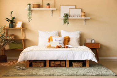 Yatak odasının içinde dizüstü bilgisayarı, kahvaltısı ve yatağında kitapları var.