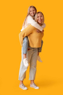 Güzel bir kadın ve sarı arka planda şık kazaklar giyen tatlı kızı.