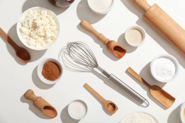 Beyaz arka planda tatlı tarçınlı rulo hazırlamak için farklı malzemeler