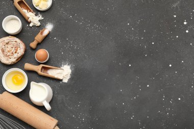 Tatlı tarçınlı rulo ve siyah arka planda farklı malzemeler.