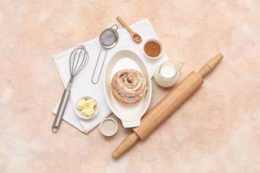 Tatlı tarçınlı fırın yemeği ve bej arka planda farklı malzemeler.