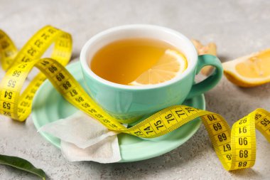 Limon dilimli bir fincan diyet çayı ve arka planda mezura. Kilo verme konsepti