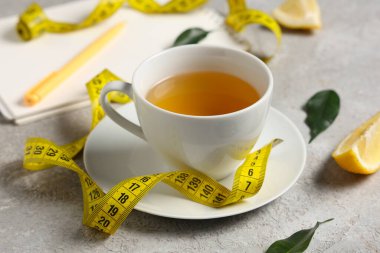 Kilo kaybı, not defteri, limon ve grunge masasındaki mezura için bir fincan çay, yakın plan.