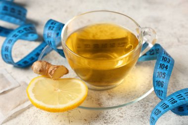 Kilo vermek için bir fincan çay ve beyaz grunge masasındaki şerit, yakın plan.