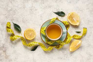 Kilo vermek için bir fincan çay, limon ve beyaz grunge masasında mezura.