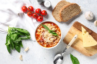 Bowl of pasta fagioli with cheese and ingredients on white background clipart