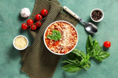 Bir kase fagioli makarna ve yeşil arka planda malzemeler.