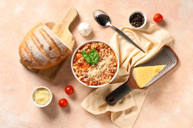 Bowl of pasta fagioli with ingredients and bread on beige background clipart