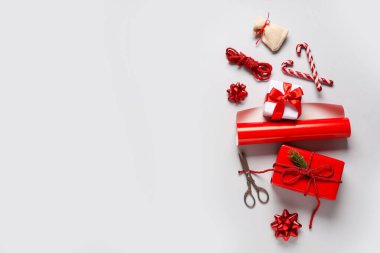 İçinde ambalaj malzemeleri ve gri arka planda farklı dekorasyonlar olan Noel hediyesi kutuları.