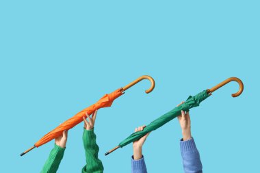 Mavi arka planda şemsiyeli kadın elleri