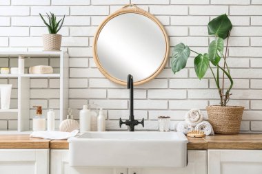 Banyo malzemeleri, raf ve lavabo banyodaki beyaz tuğla duvarın yanında.