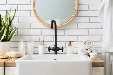 Lavabo, banyo malzemeleri ve banyoda beyaz tuğla duvarın yanında lavabo.
