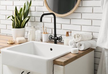 Lavabo, banyo malzemeleri ve banyoda beyaz tuğla duvarın yanında lavabo.