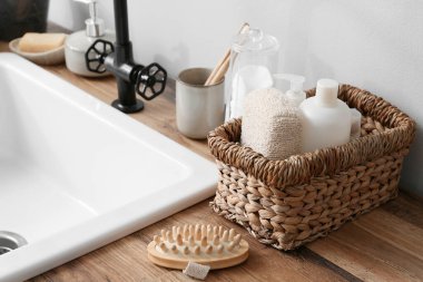 Banyoda beyaz duvarın yanındaki ahşap masada banyo aksesuarları.