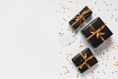 Gri arka planda siyah hediye kutuları ve altın konfeti