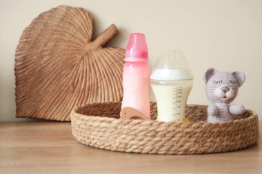Ağaç mutfak tezgahında bebek sütü formülü ve oyuncaklarıyla dolu bir sepet.