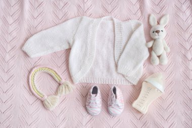 Şık bebek kıyafetleri, patiler, oyuncaklar ve pembe ekose üzerinde bebek sütü formülü olan kompozisyon