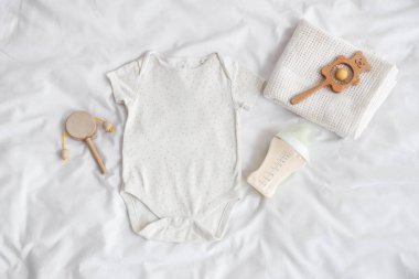Bebek sütü formülü, vücut giysisi, hafif yatakta çıngırak ve ekose kumaş.